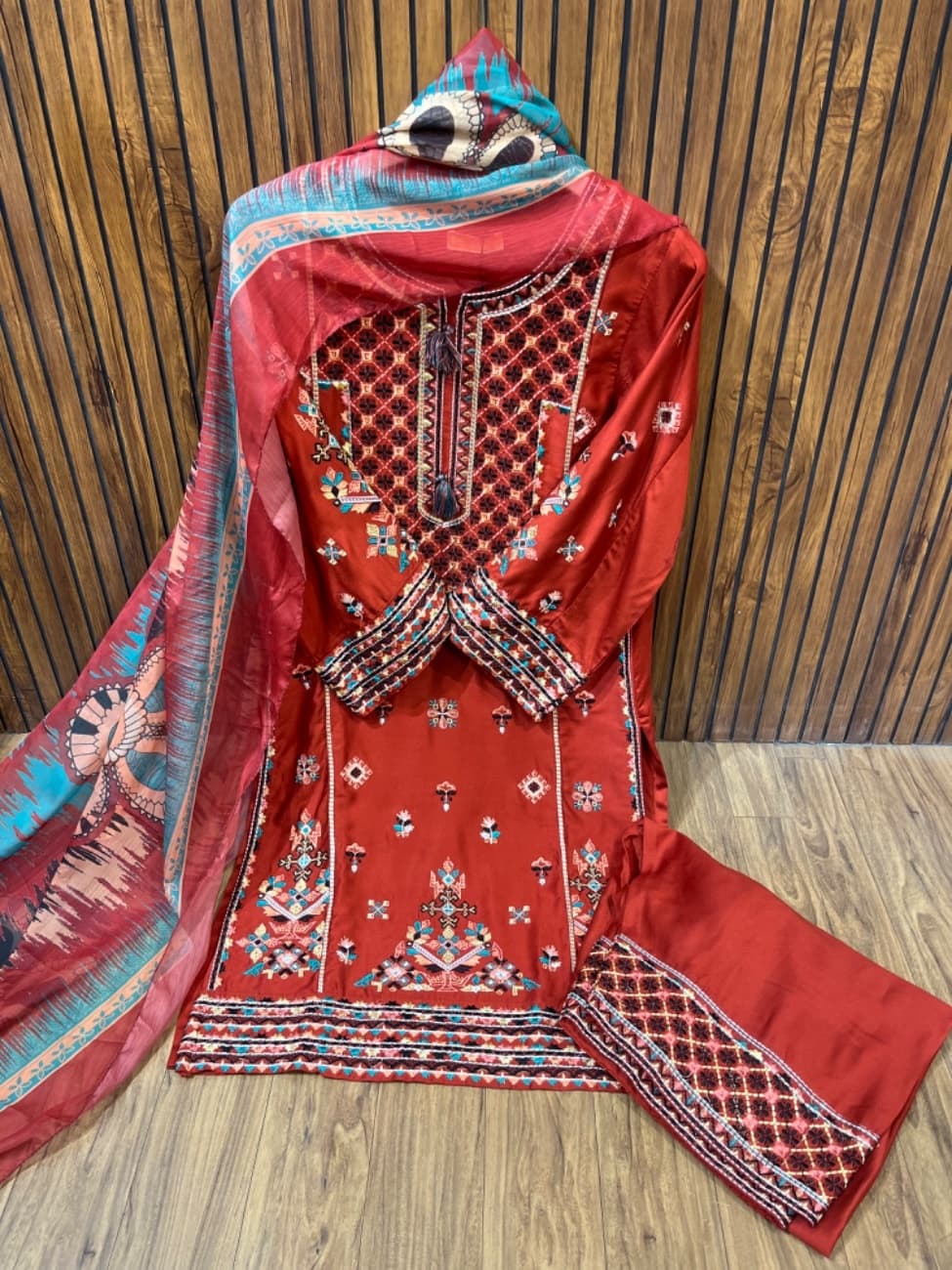 Elegant rust colour embroidery suit featuring intricate multicolor thread work on the neckline, daman, sleeves, and plazo border paired with a beautifully printed dupatta for a rich festive and party wear look.