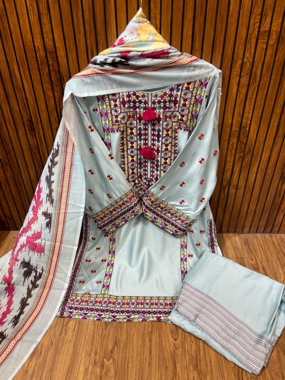 Elegant light green suit featuring intricate multicolor ethnic embroidery on the neckline, daman and sleeves with stylish tassel detailing, paired with a matching bottom and a beautifully printed dupatta